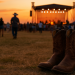 Cowboy boots in a field with a stage in the background.